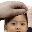 a person is touching a child 's head with a towel .