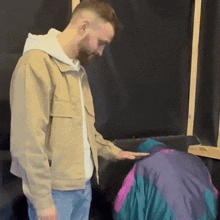 a man in a tan jacket is standing next to a woman in a purple jacket