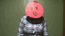 a woman wearing a plaid shirt has an angry face drawn on a piece of paper