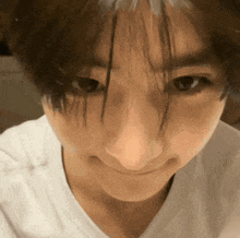 a close up of a person 's face with long hair and a white shirt on .