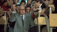 a man in a suit and tie is sitting in front of a crowd of people in a lecture hall .