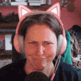 a woman wearing pink headphones with cat ears making a funny face