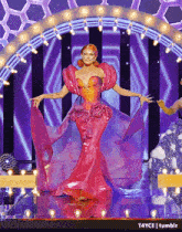 a woman in a pink dress is dancing on a stage with a purple background