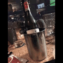 a bottle of wine sits in a silver bucket on a table