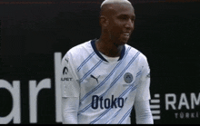 a soccer player wearing a white and blue striped jersey with the word toko on it