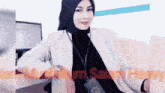 a woman wearing a hijab and a lanyard with the letter b on it is sitting on a couch