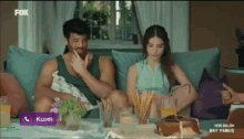 a man and a woman sit on a couch with a fox logo on the bottom left