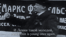 a man stands in front of a sign that says " and lenin is young once again " on it