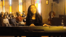 a woman is singing while playing a keyboard in front of a church