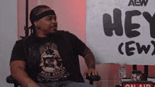 a man sitting in front of a sign that says hey crew