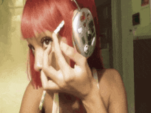 a woman with red hair is wearing headphones and putting makeup on