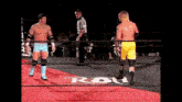 two wrestlers are standing in a ring with a sign that says row