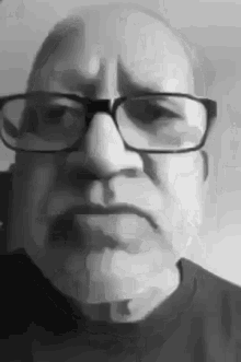 a man with glasses and a mustache is making a funny face in a black and white photo .