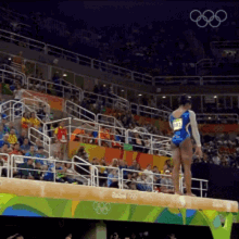 a female gymnast is standing on a balance beam in front of a crowd at the olympics