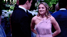 a man in a tuxedo and a woman in a pink dress are standing next to each other