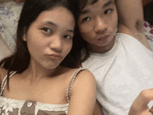 a woman making a funny face next to a man in a white tank top