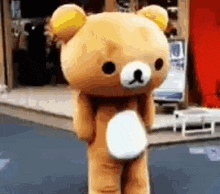 a teddy bear with a yellow ear is standing on a street