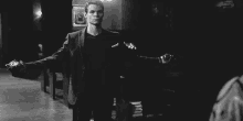 a black and white photo of a man standing in front of a piano .