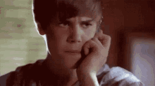 a young man is talking on a cell phone while holding his hand to his face .
