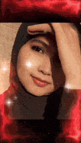 a woman wearing a black hijab is smiling with a red background