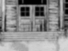 it is a black and white photo of a house with a porch and windows .