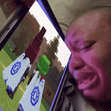 a person is crying while looking at a minecraft game on a tablet