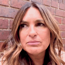 a close up of a woman 's face against a brick wall