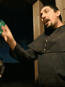 a man in a black robe is holding a green box in his hand