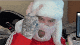 a man wearing a white ski mask and a red sweater is giving a peace sign