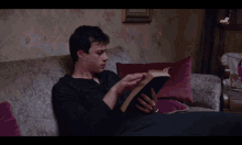 a man sits on a couch reading a book called the bible