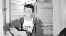 a young man is playing an acoustic guitar in a black and white photo .