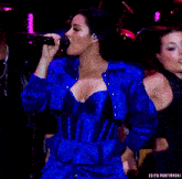 a woman in a blue dress is singing into a microphone with the words edits portirroni behind her