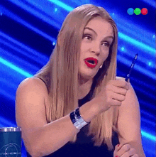 a woman holding a pen in front of a blue background that says gran hermano