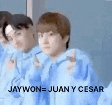 a group of young men in blue sweatshirts are standing next to each other and pointing at the camera .