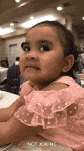 a little girl is making a funny face while sitting at a table in a restaurant .