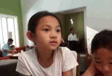 a little girl in a white shirt looks at something