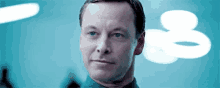 a close up of a man 's face in a blue room with a blurred background .