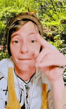a man wearing a beanie and overalls is making a face with his hand