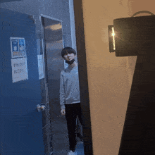 a man wearing a mask is standing in front of a door with a sign on it that says ' a warning '