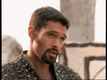 a man with a beard and studded jacket is talking to someone .