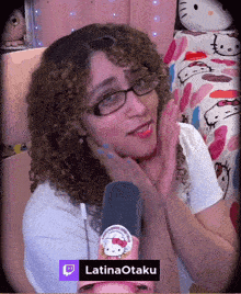 a woman with curly hair and glasses holds a hello kitty sticker in her hand and says latinaotaku on the bottom