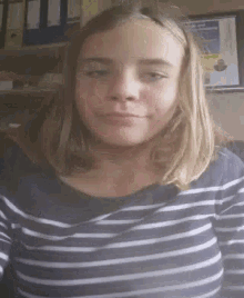 a girl with long blonde hair is wearing a striped shirt