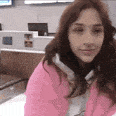 a woman in a pink sweater is sitting in front of a counter .