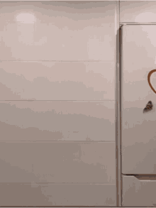 a shirtless man is standing in front of a white wall holding a towel