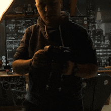 a man is holding a camera in front of a wall with a picture of new york city in the background