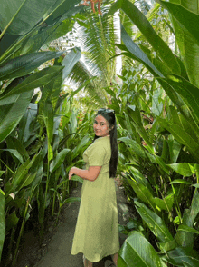 a woman in a green dress is surrounded by lots of plants