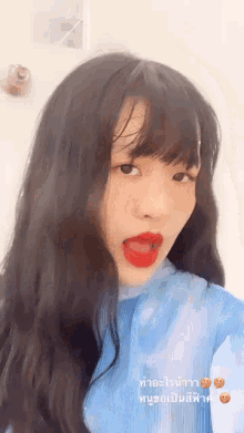 a girl with long black hair and red lipstick is taking a selfie with her mouth open .