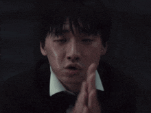 a close up of a man with his hands folded in prayer