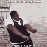 a man is dancing in front of a brick wall with the caption glen smith is pleased with the current state of affairs