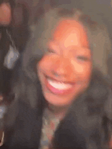 a close up of a woman 's face with a blurred background smiling .